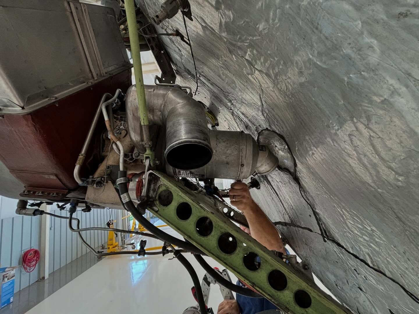 A man is working on a pipe on the side of a building.