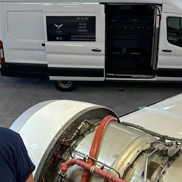 A man is working on a plane engine in front of a van.