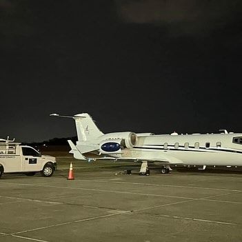 A small private jet is parked on the tarmac at night.