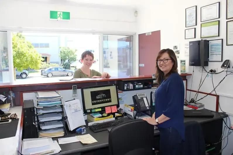 Two Women Are Standing In Front Of A Desk With A Computer — Currimundi Automotive Service In Warana, QLD