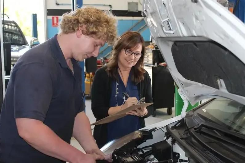 A Man And A Woman Are Looking Under The Hood Of A Car — Currimundi Automotive Service In Warana, QLD