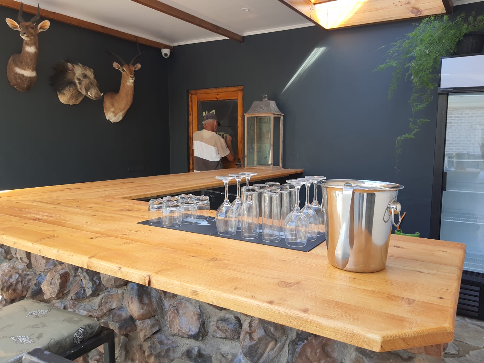 A wooden bar with glasses and a bucket on it.