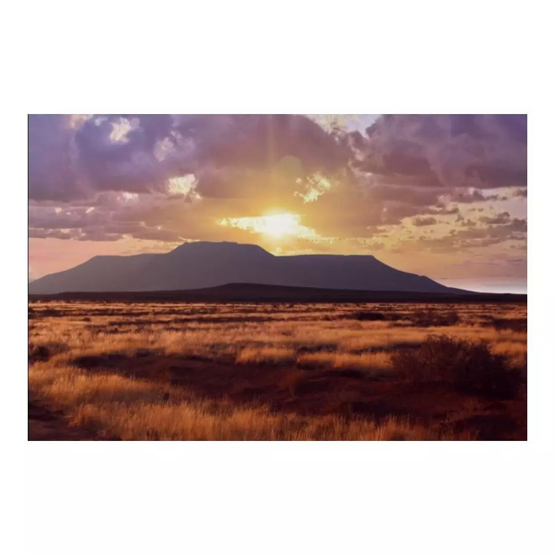 A sunset over a desert landscape with mountains in the background
