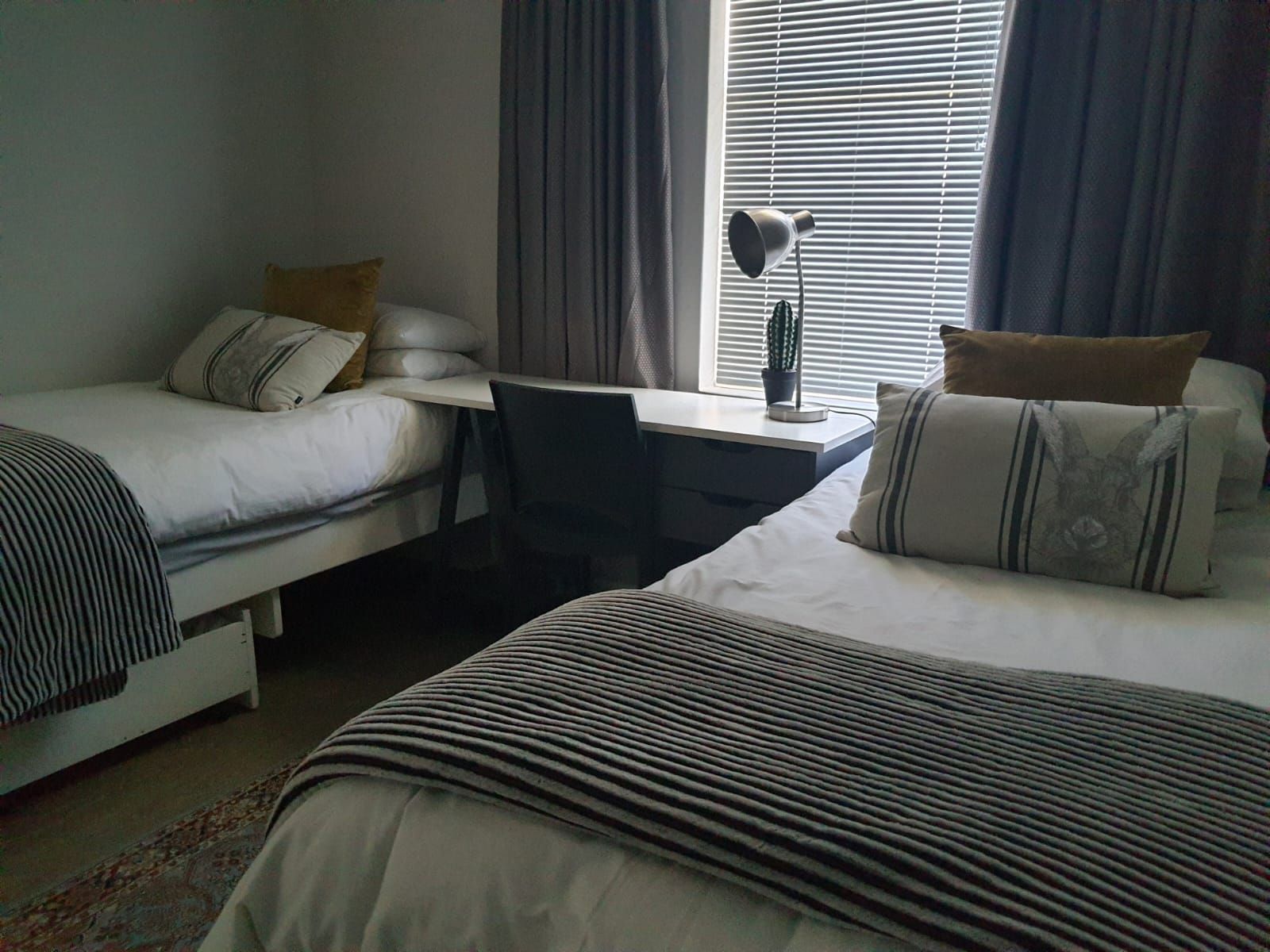 A bedroom with two beds , a desk and a window.