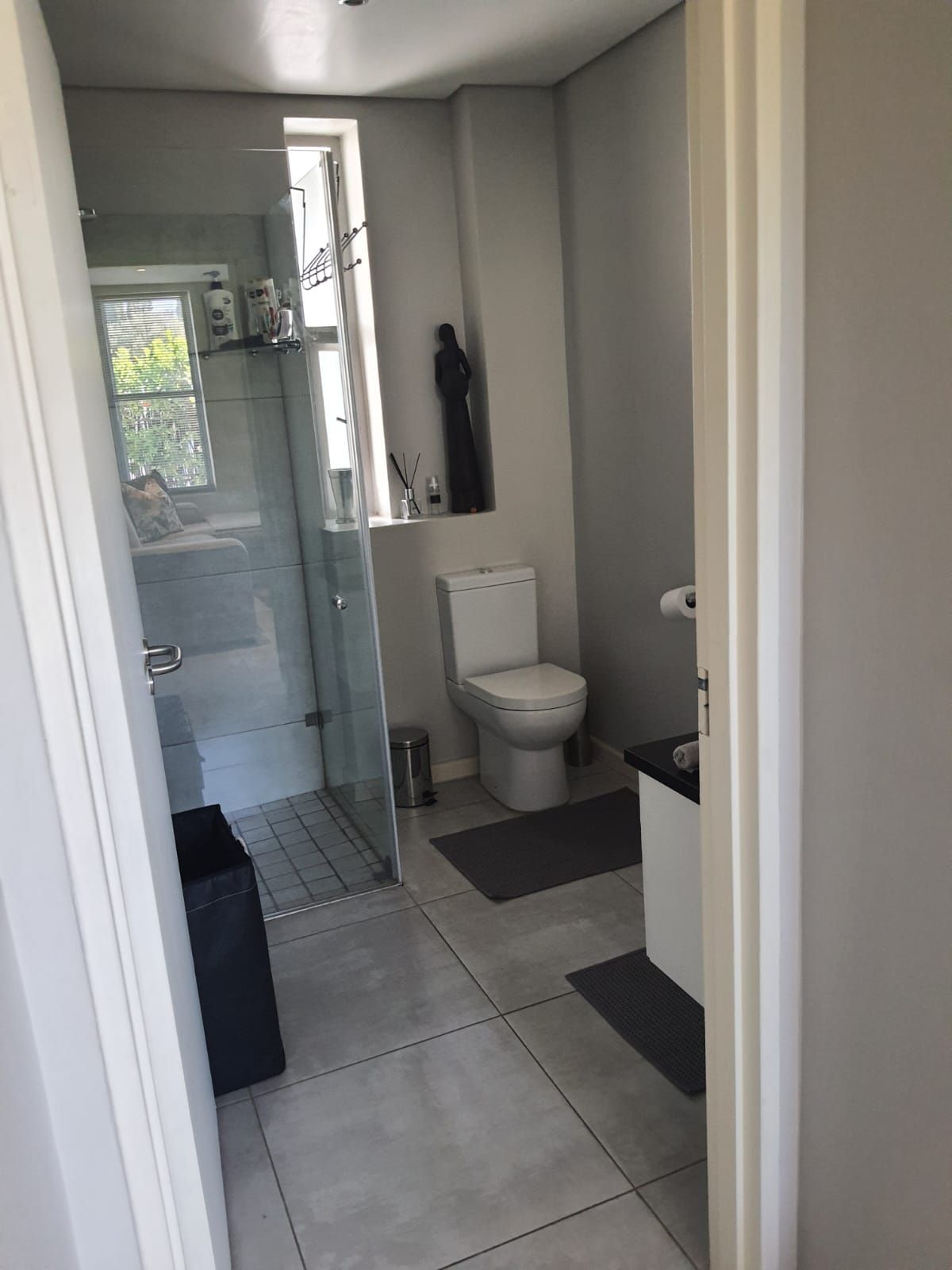 A bathroom with a toilet , sink and shower.