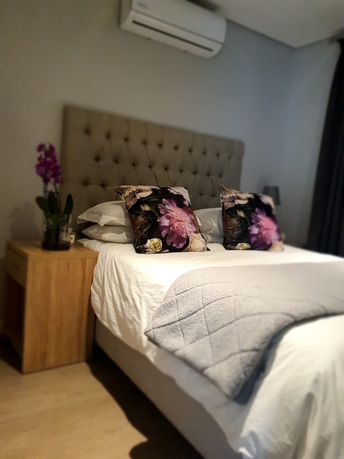 A bedroom with a bed , nightstand , and air conditioner.