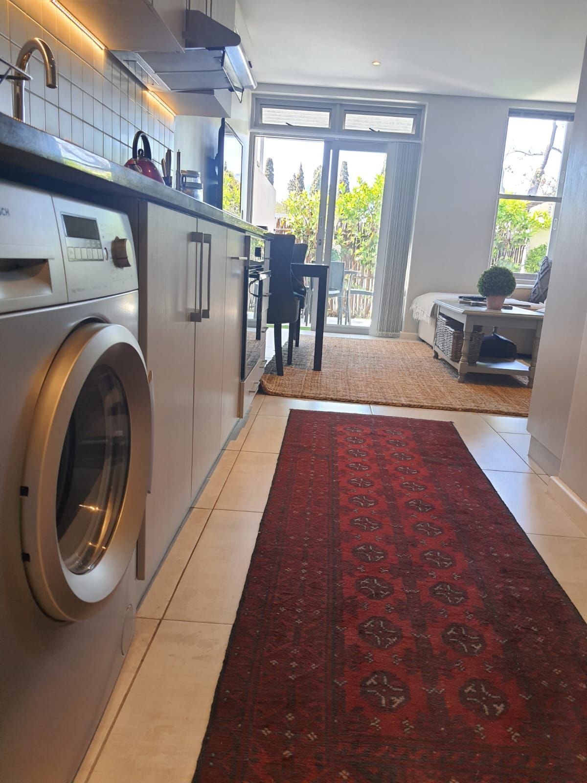 A kitchen with a washing machine and a rug on the floor.