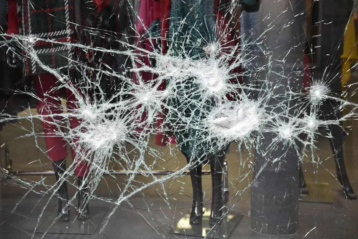 A broken glass window with a mannequin in the background