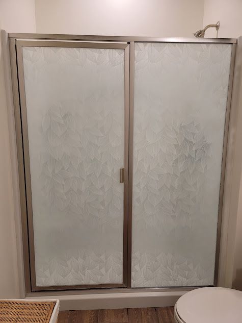 A bathroom with a sliding glass shower door and a toilet.