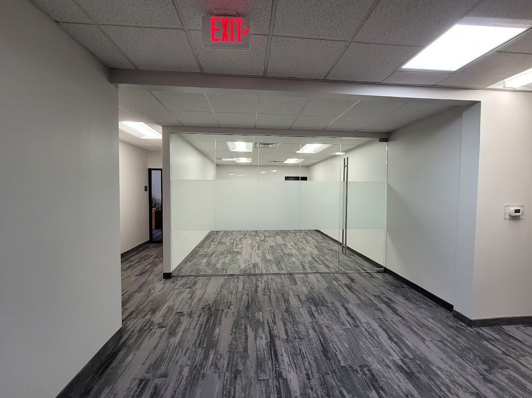 A large empty room with a red exit sign on the ceiling.