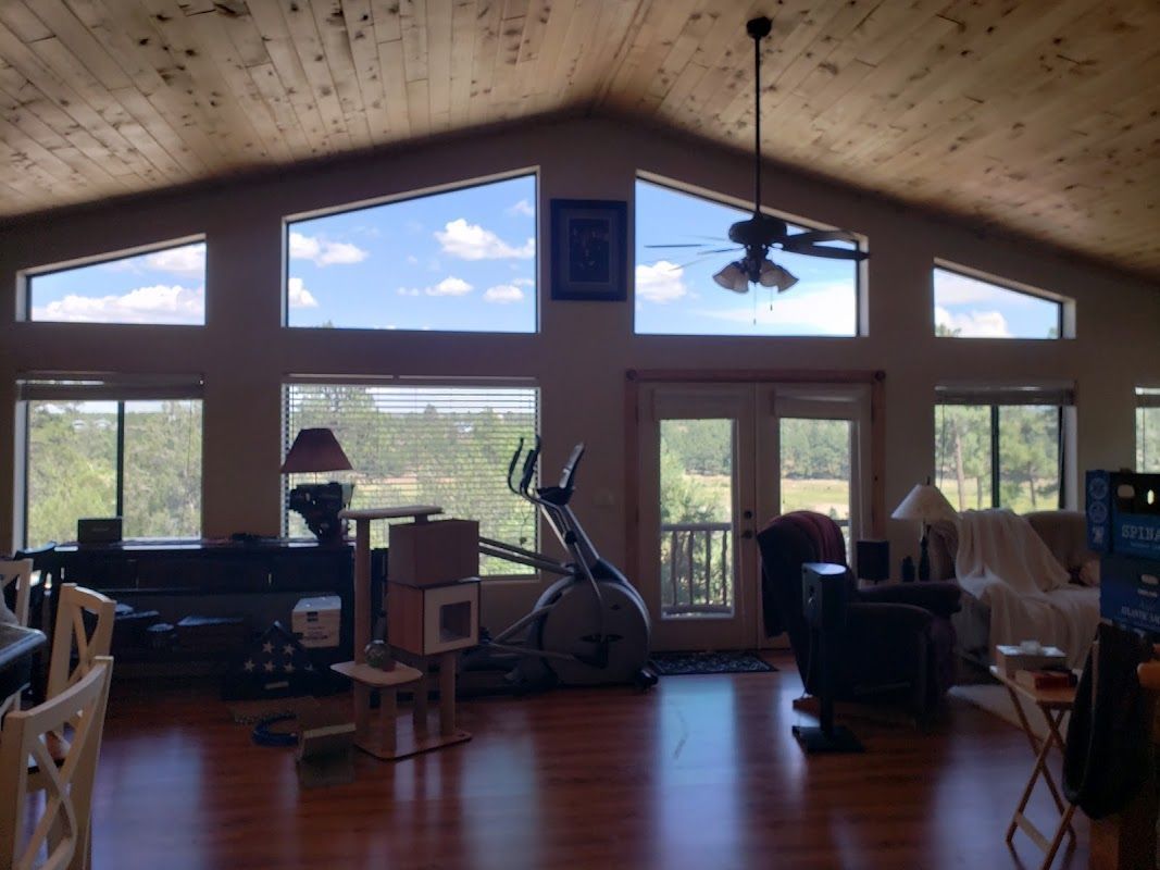 A living room with a lot of windows and a ceiling fan
