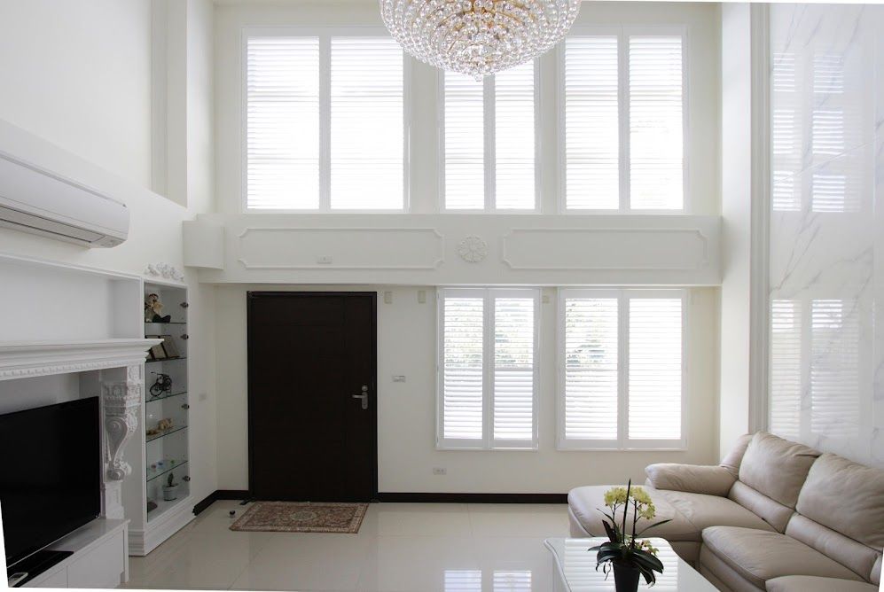 A living room with a couch , television , and chandelier.