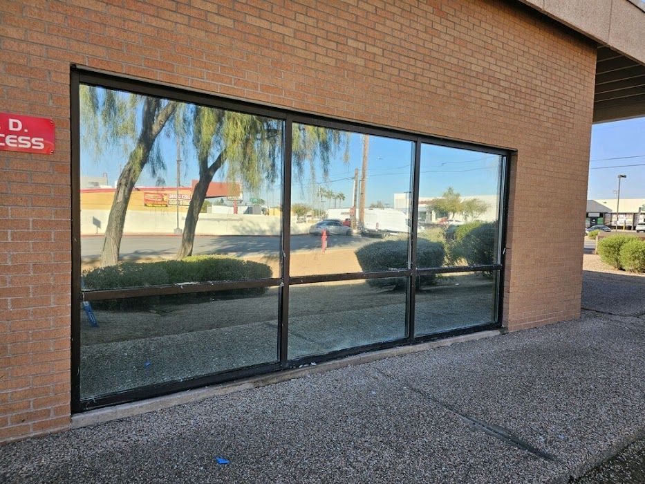 A brick building with a large window with a reflection of trees in it.