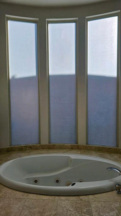 A jacuzzi tub in a bathroom with three windows.