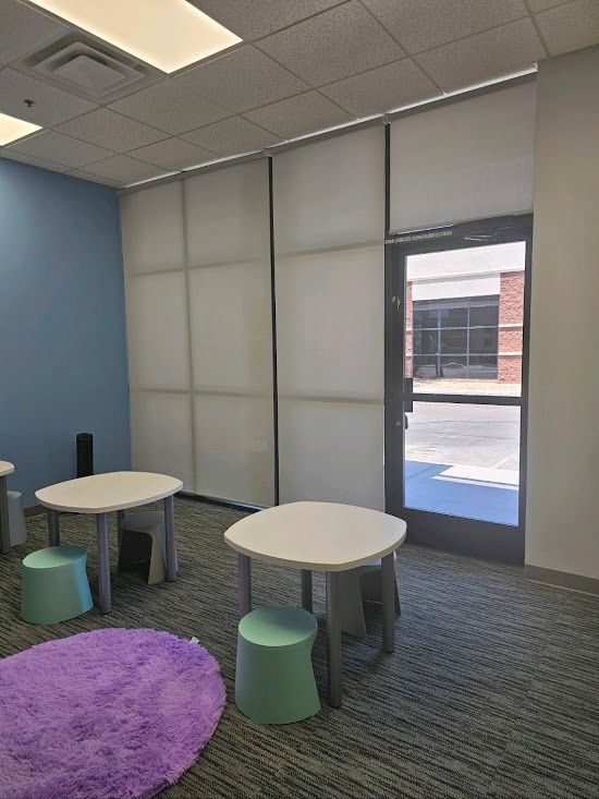 A room with tables and stools and a purple rug