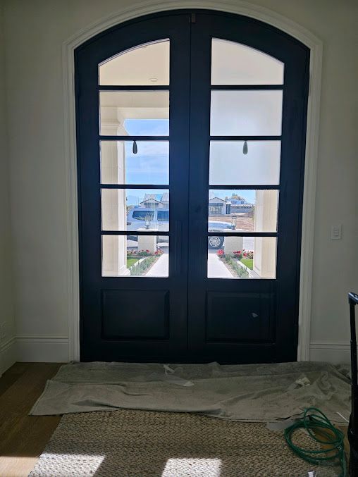 A pair of black doors with arched windows in a room.