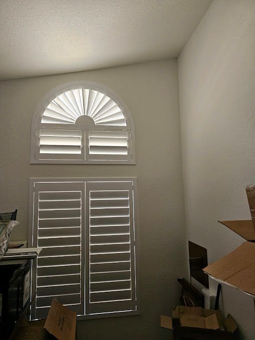 A room with boxes and a window with shutters on it.