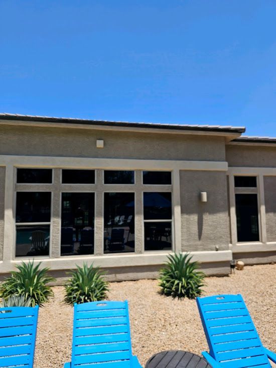 A house with a lot of windows and blue chairs in front of it