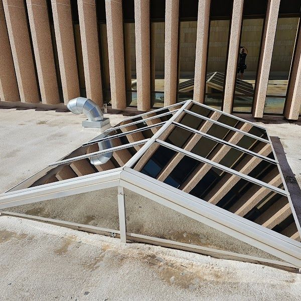 A skylight on the roof of a building with a ventilation pipe attached to it.