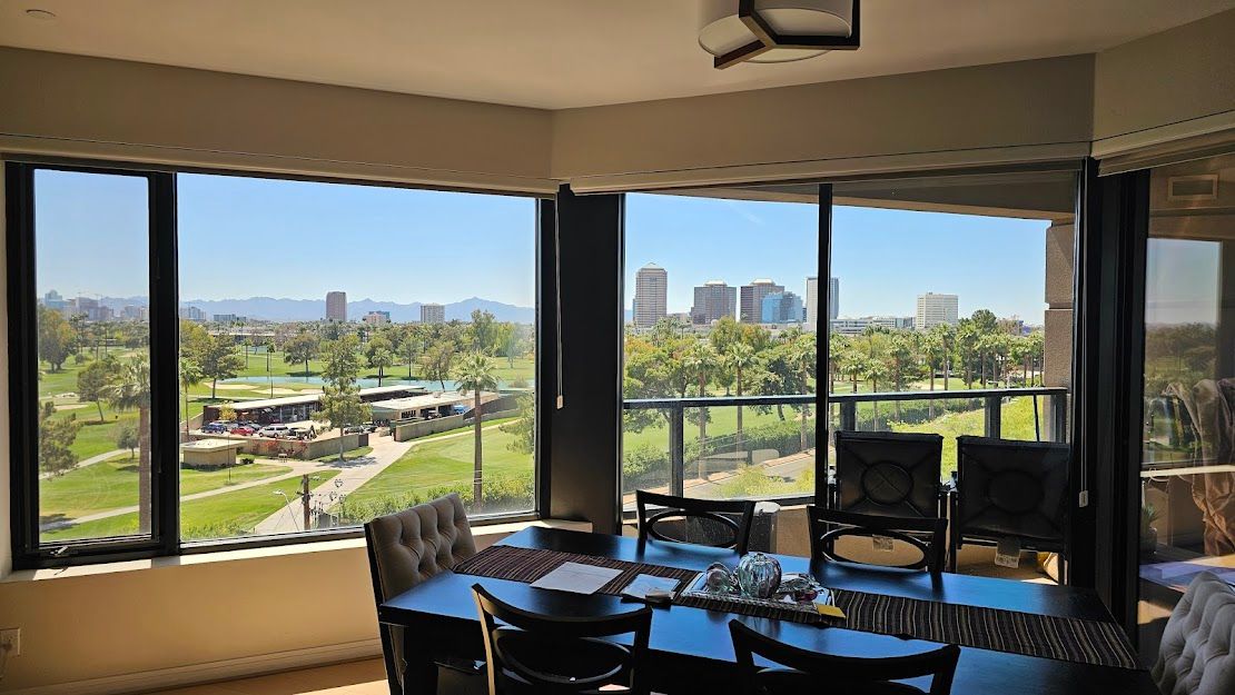 A dining room with a table and chairs and a view of a park.