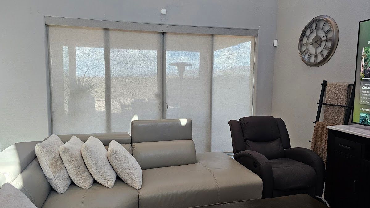 A living room with a couch and a chair and a clock on the wall.