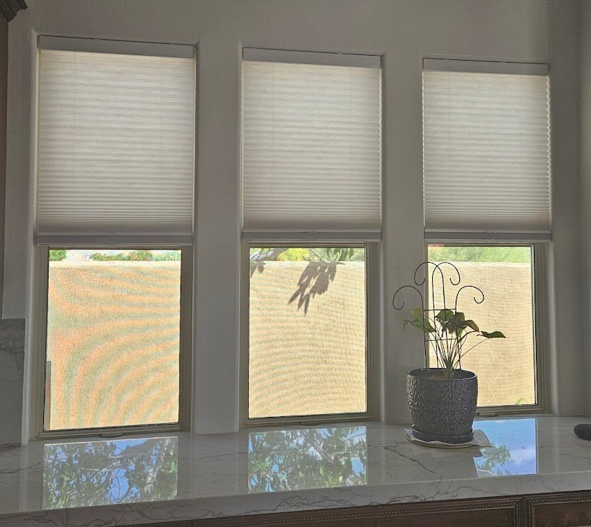 A kitchen with three windows and a potted plant on the counter.