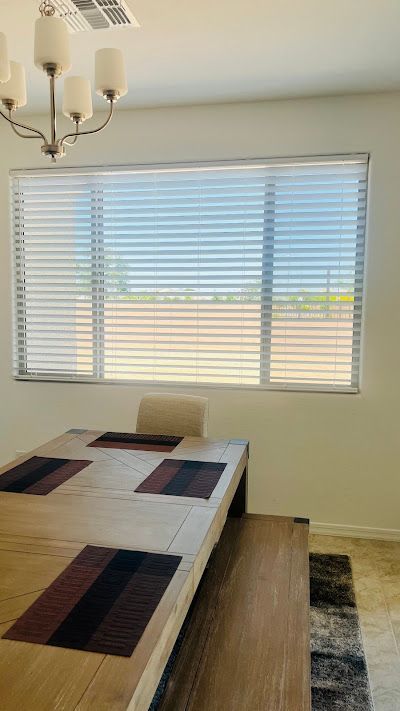 A dining room with a table and chairs and a window with blinds.