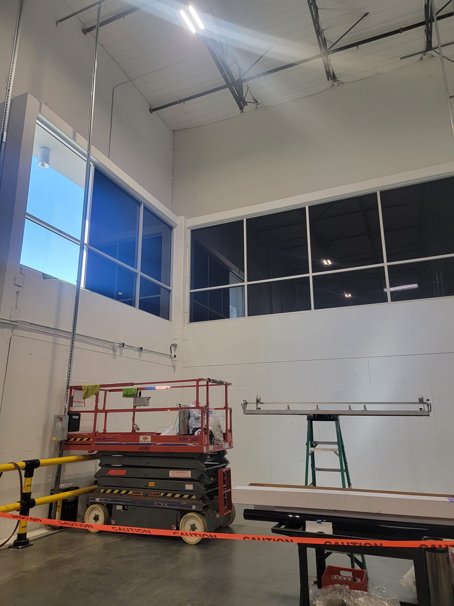 A large room with a lot of windows and a scissor lift.
