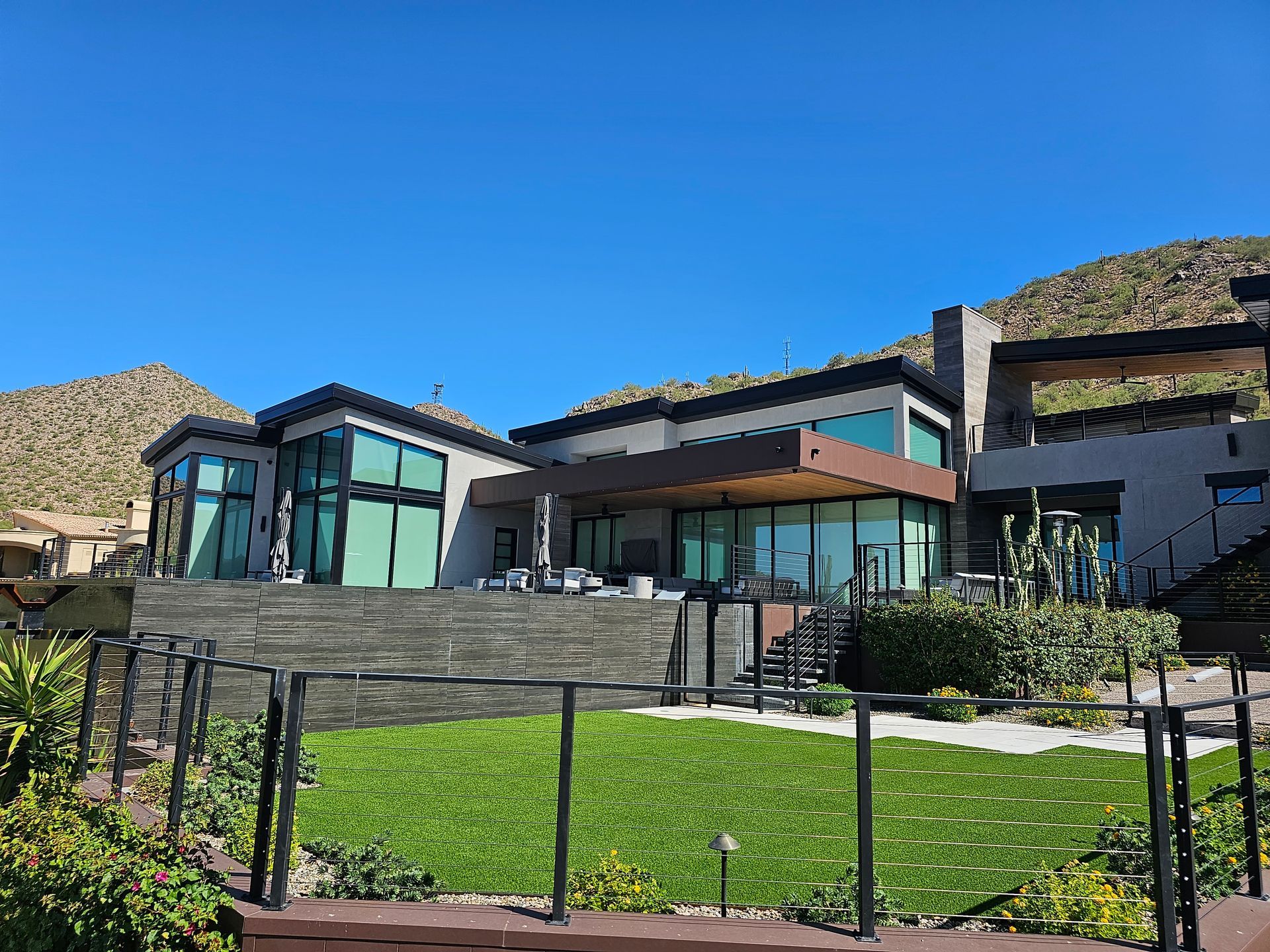 A large house with a lot of windows is sitting on top of a lush green hillside.