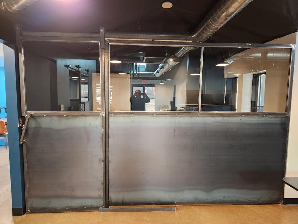 A man is taking a picture of himself in a mirror in a room with a metal wall.