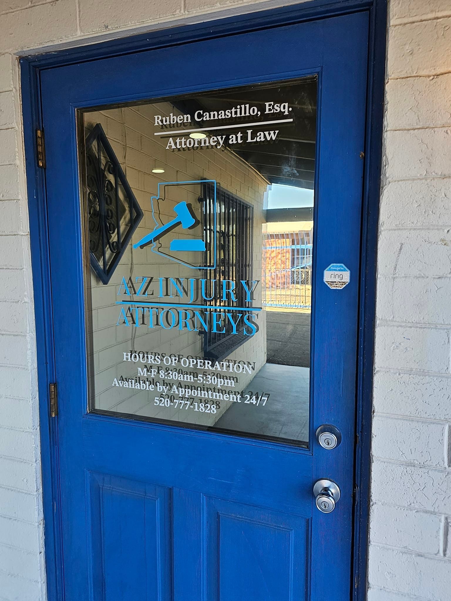 A blue door with a mirror on it is on a white brick building.