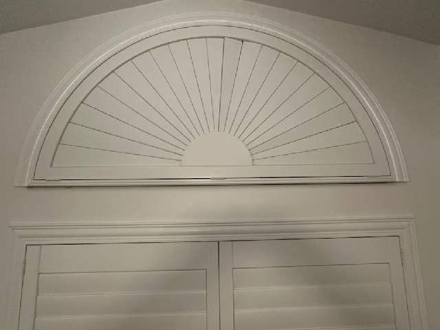 A white window with a fan shaped arch above it.