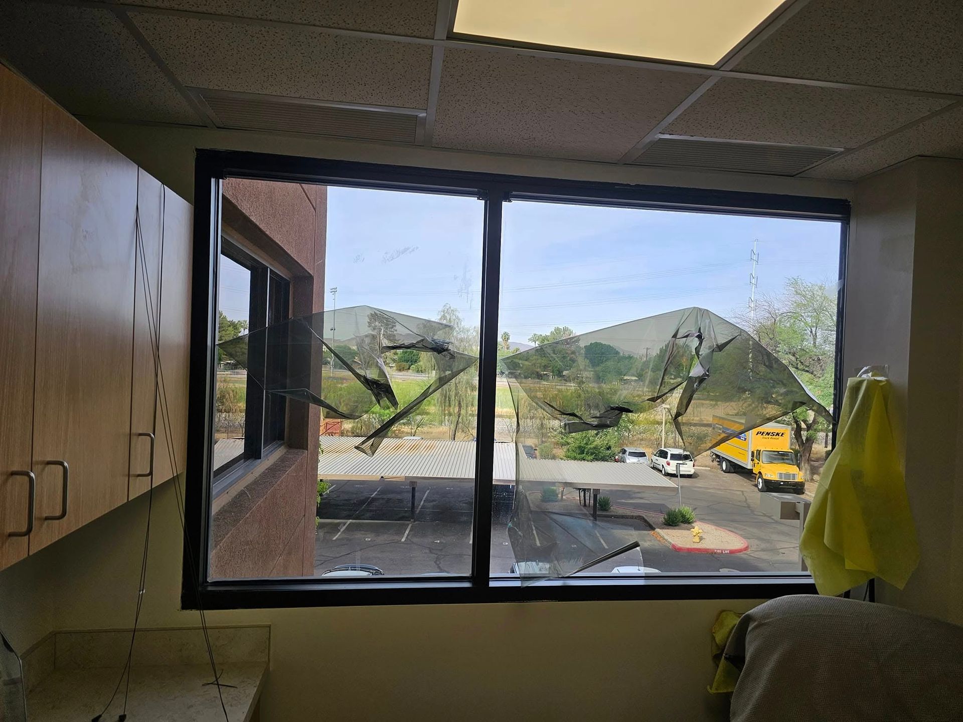 A broken window in a room with a yellow school bus in the background.