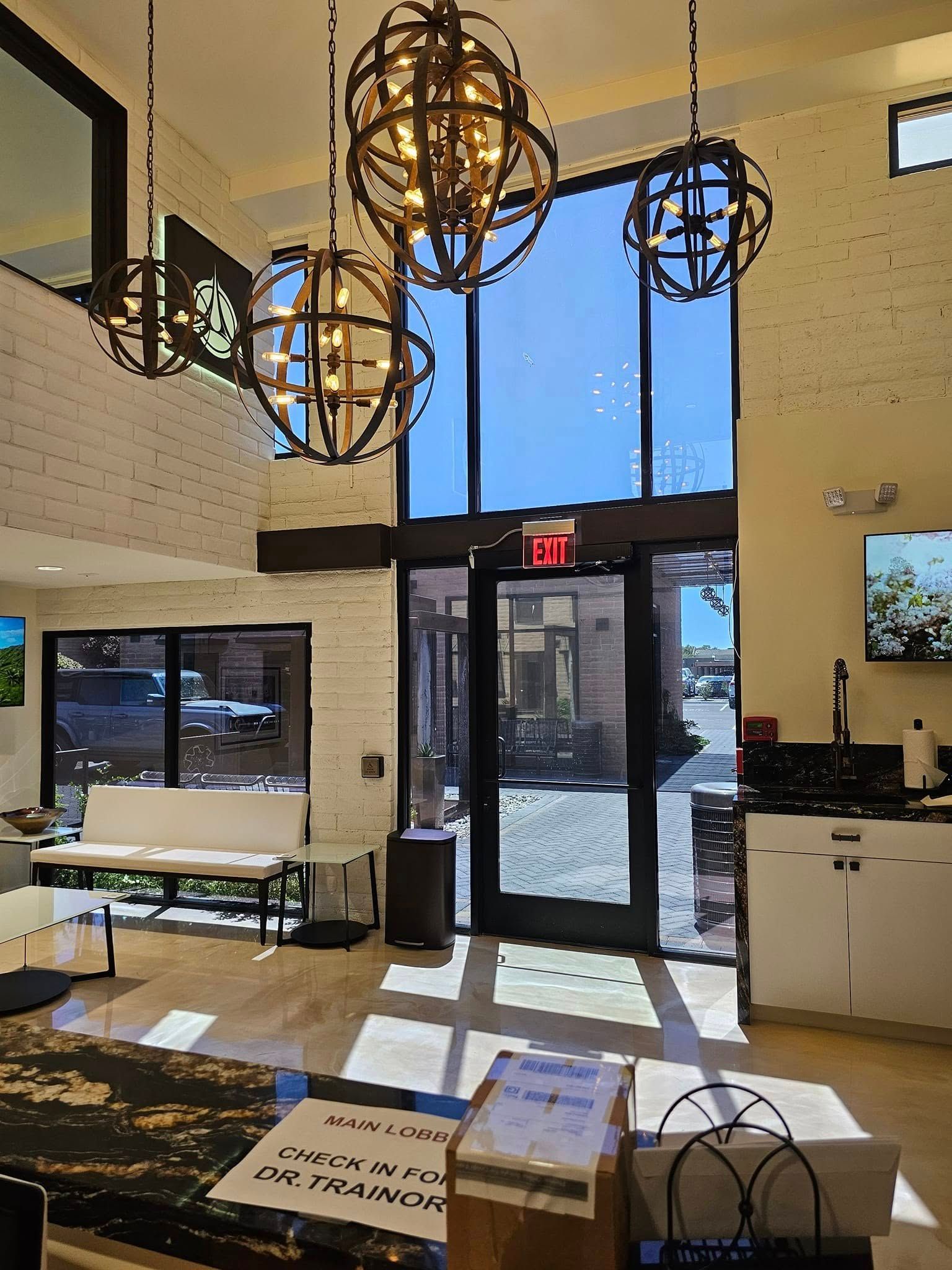 A living room with a lot of windows and chandeliers hanging from the ceiling.