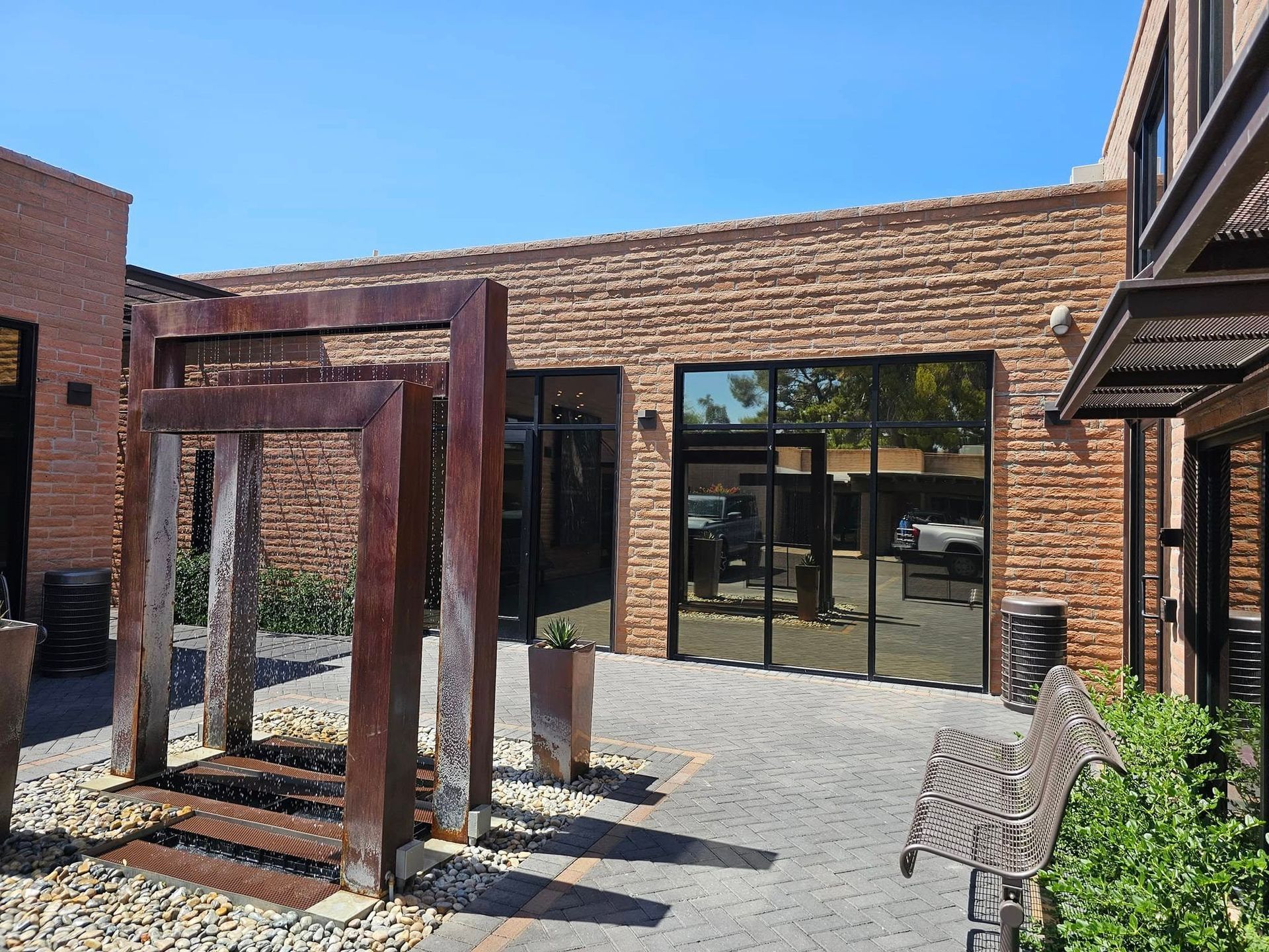 A brick building with a lot of windows and a bench in front of it.