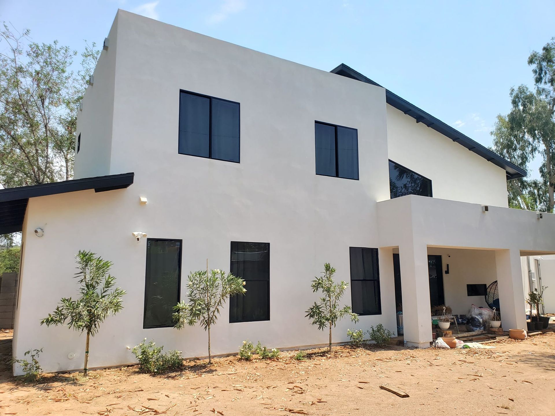 A white house with black windows is surrounded by trees