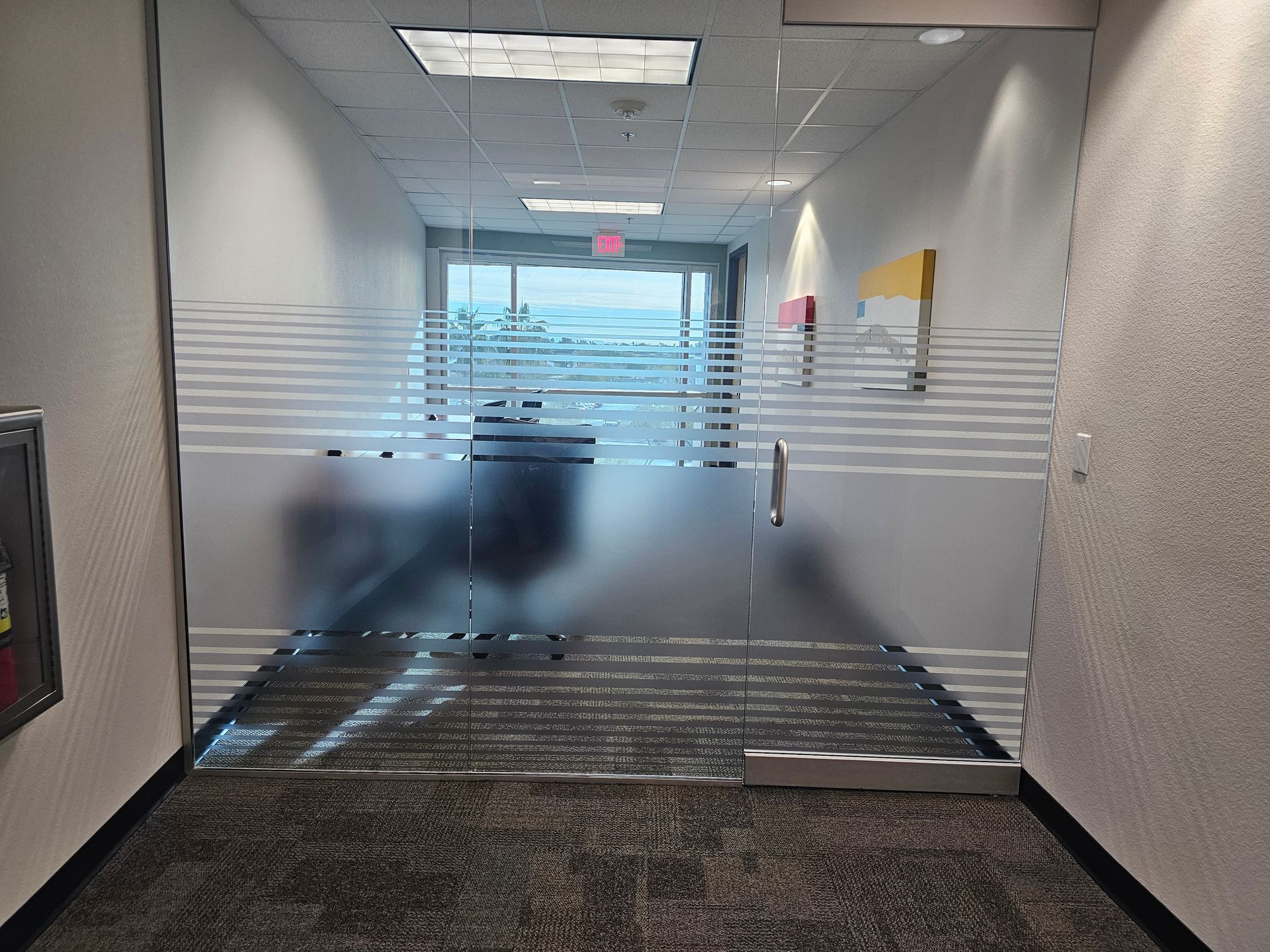 A hallway with a glass door and a fire extinguisher
