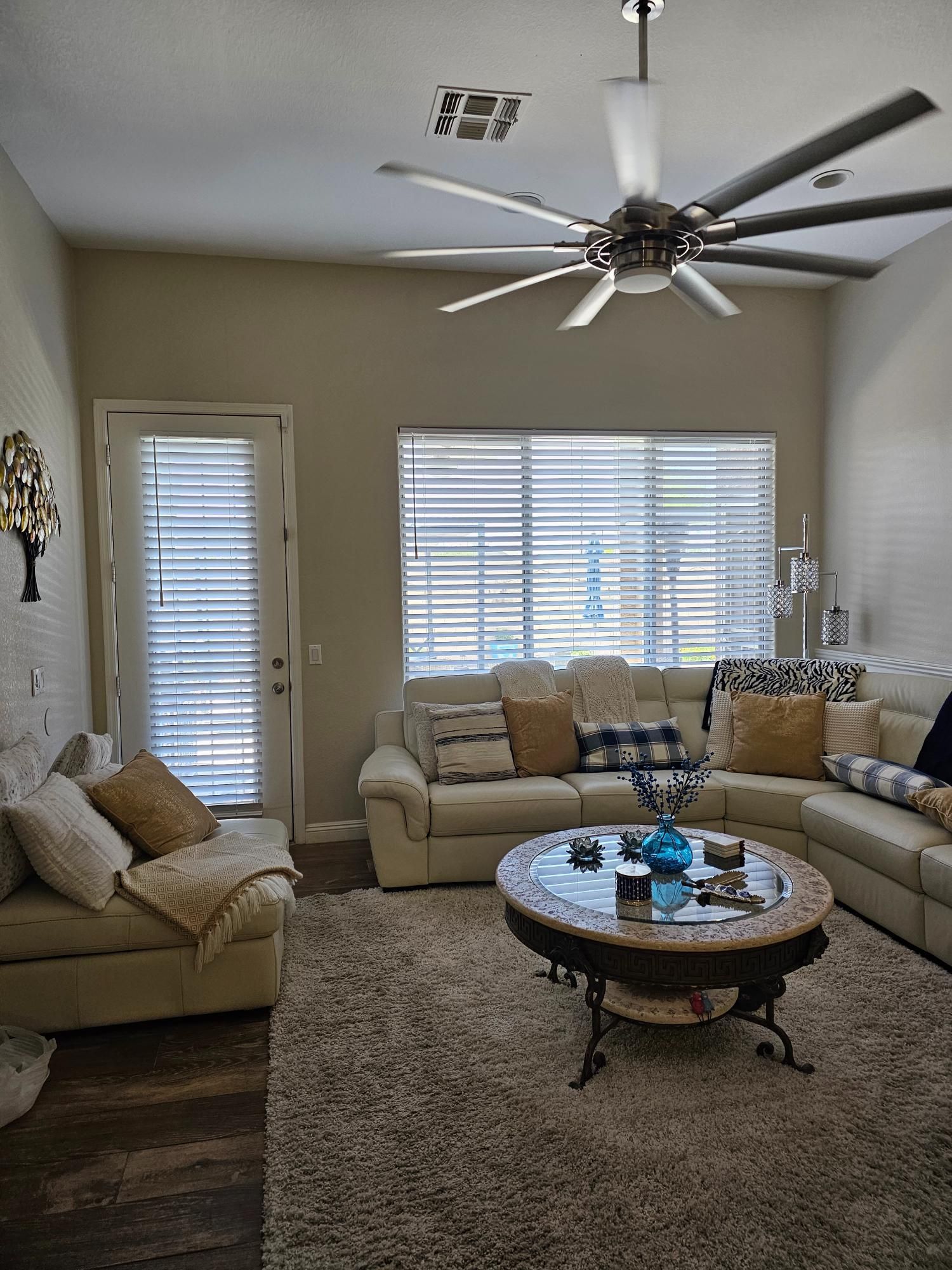 A living room with a couch , coffee table , and ceiling fan.