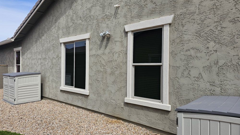 There are two windows on the side of a house.