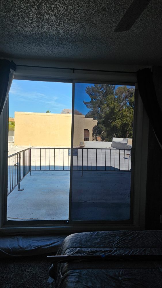 A bedroom with a sliding glass door leading to a balcony.