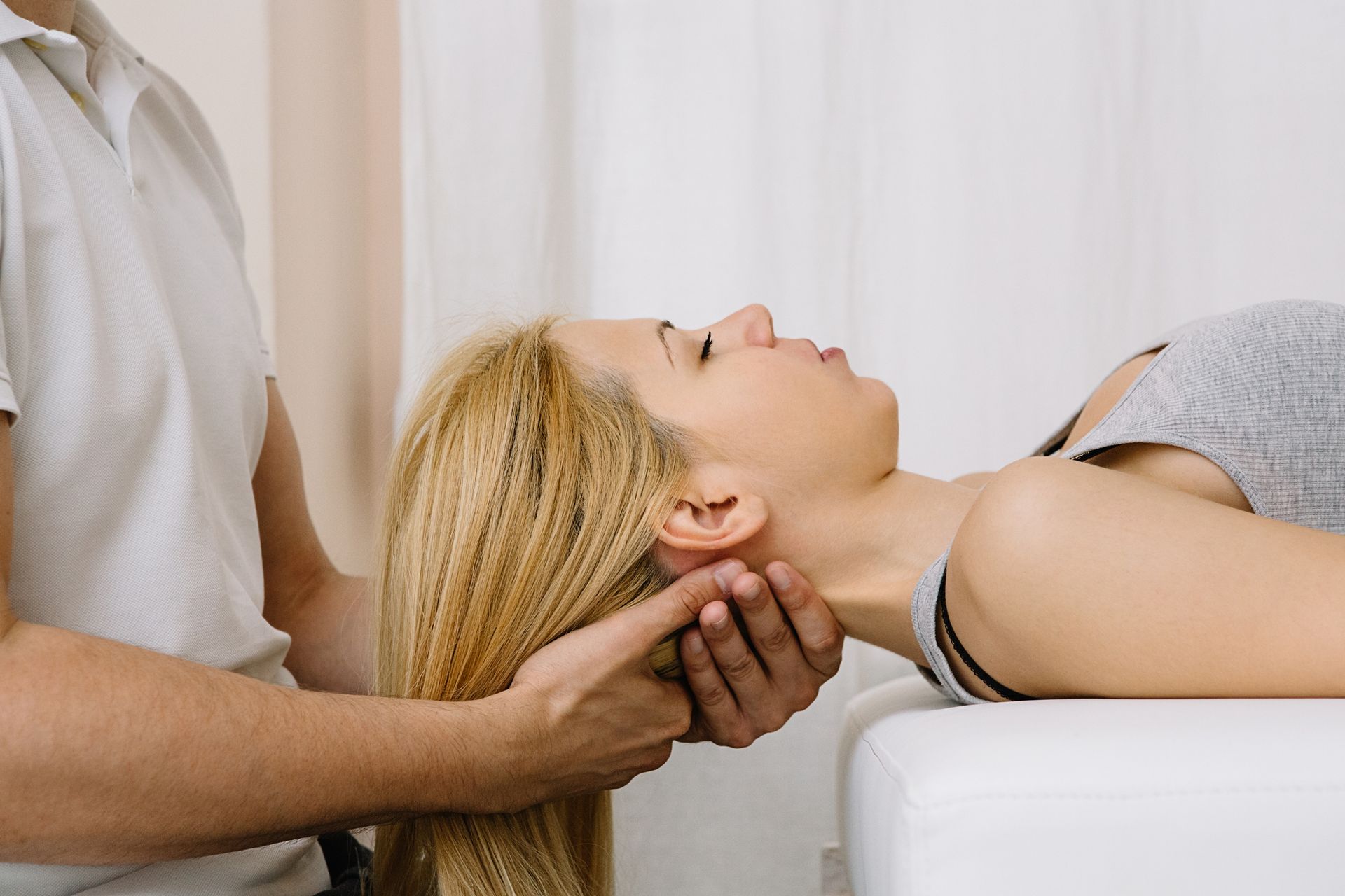 A woman is laying on a table getting a head massage from a man.