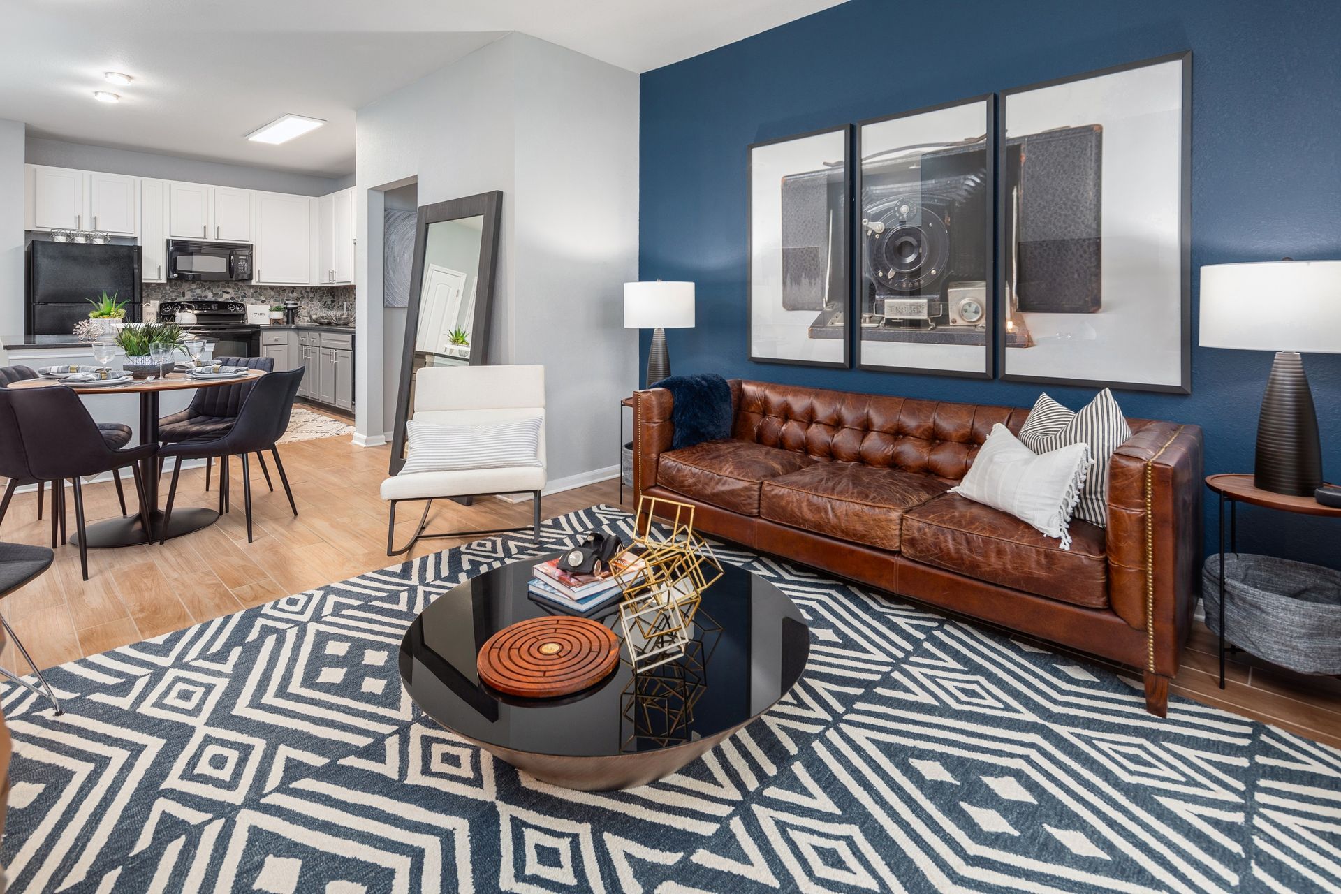 A living room with a couch , chair , coffee table and a painting on the wall.