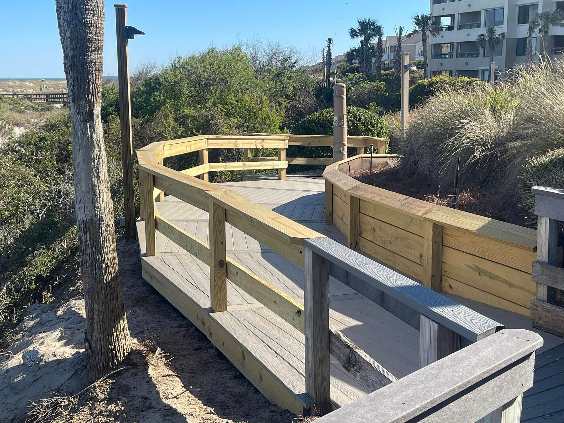 A wooden walkway leading to the beach with a building in the background