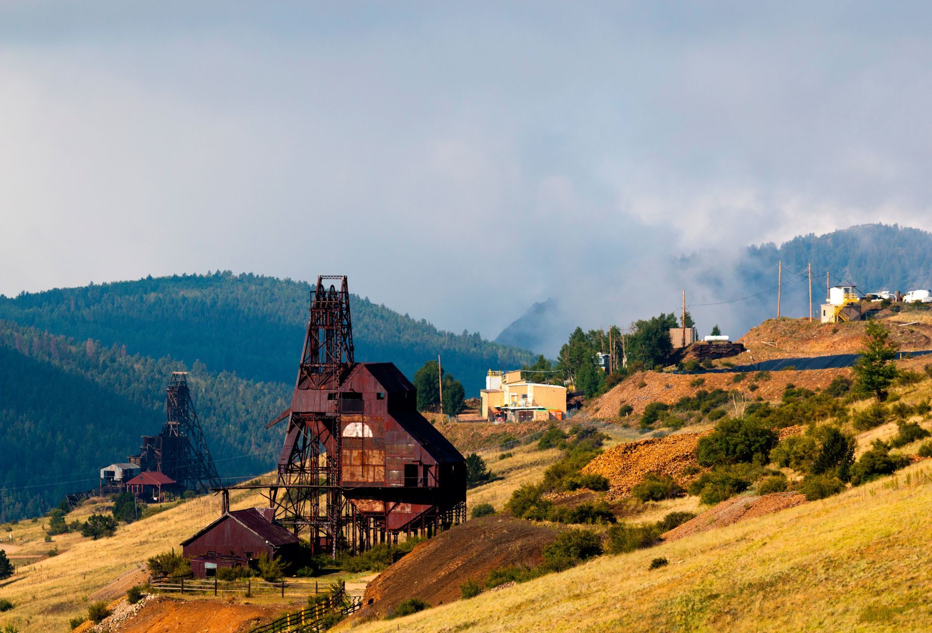 A large building is sitting on top of a hill with mountains in the background.