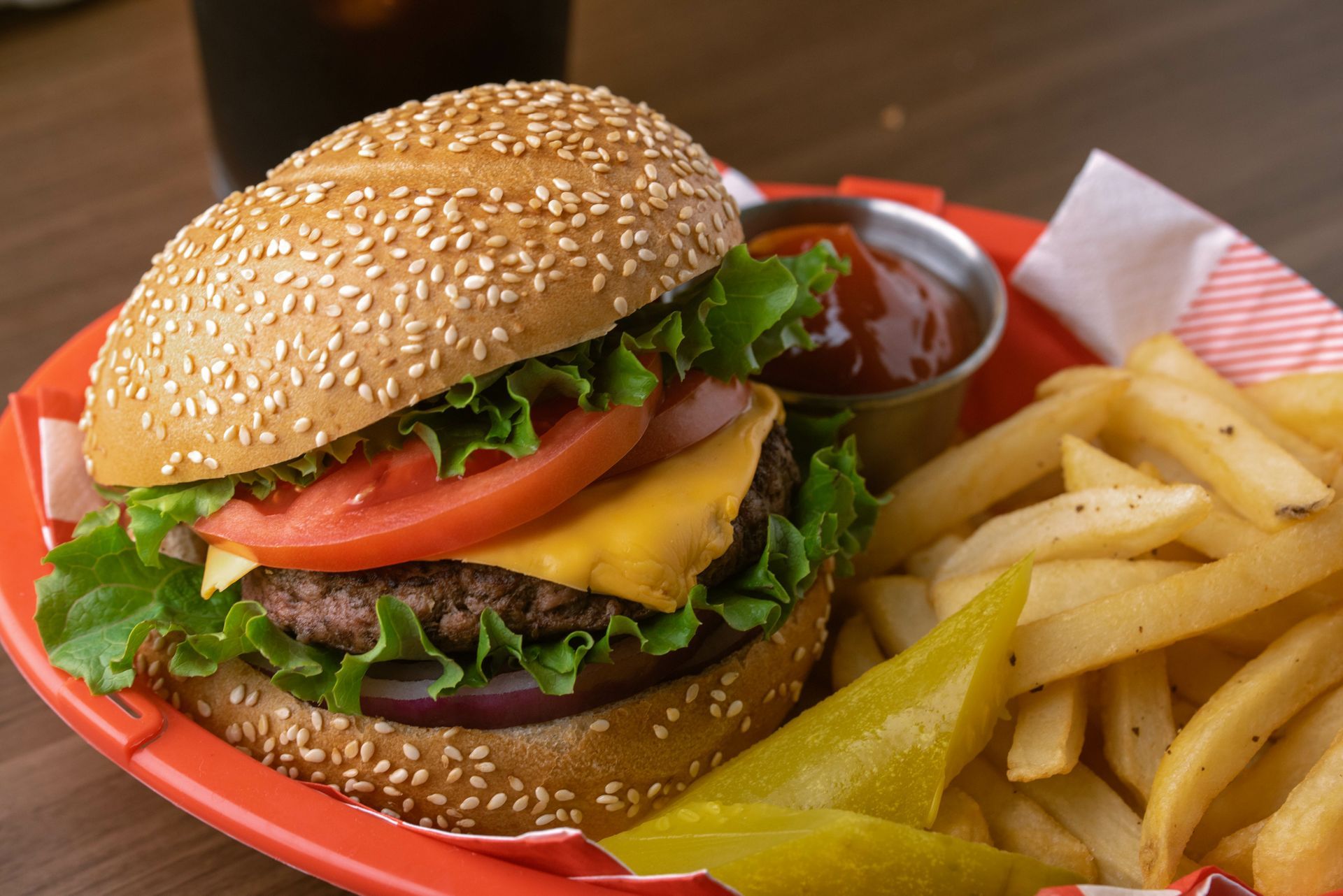 A hamburger and french fries are on a red plate.
