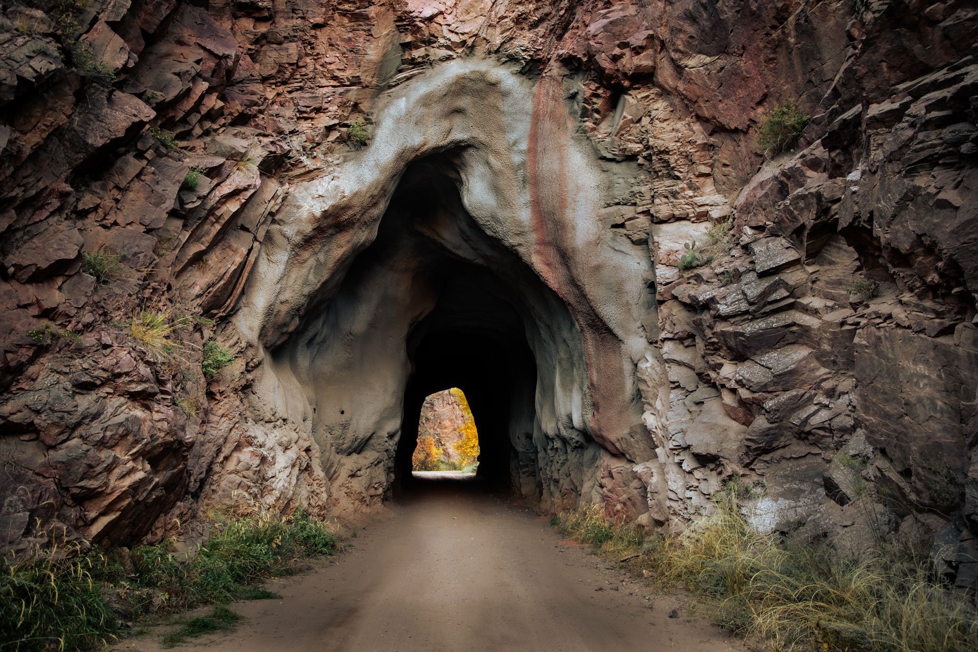 A dirt road going through a tunnel in the mountains
