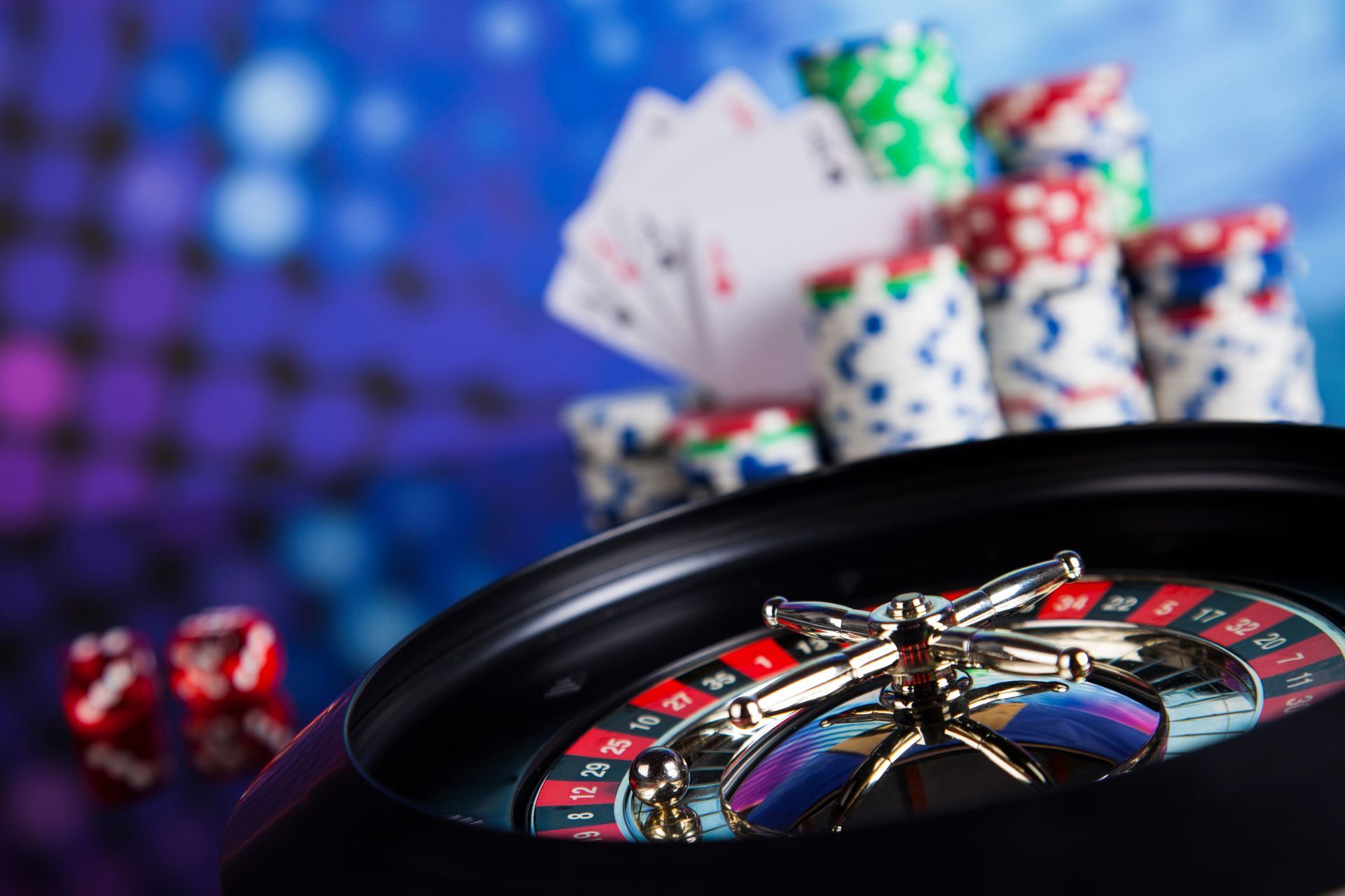 A close up of a roulette wheel with chips and cards in the background.