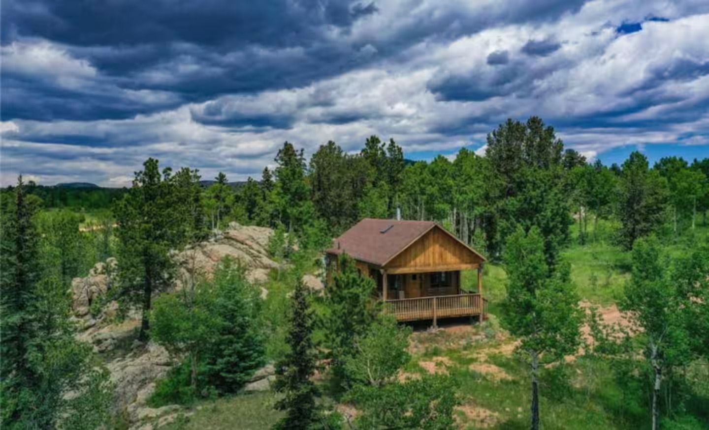 An aerial view of a cabin in the middle of a forest.