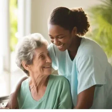 An elderly woman is sitting next to a nurse and smiling.