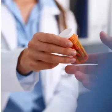 A close up of a person holding a bottle of pills.